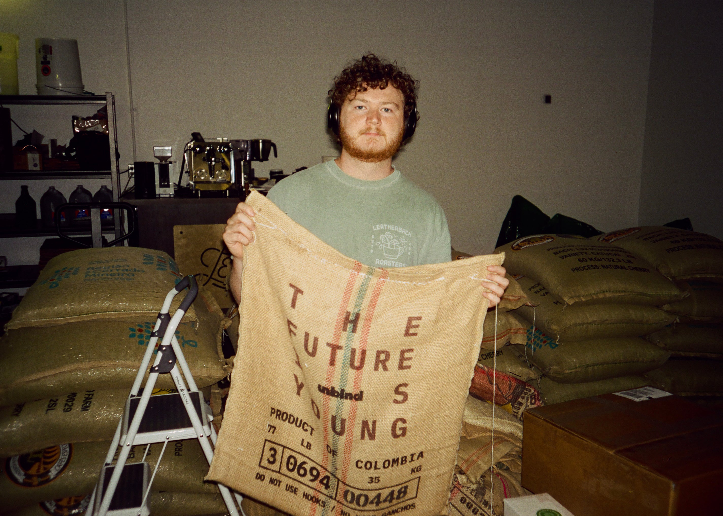 Man holding a large brown coffee sack from Unblended with text stating, "The Future is Young," in a warehouse settiing.