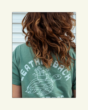 Leatherback Roasters tee shirt. Sage green sea turtle shirt back print. Grace is wearing a Large.
